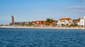 La playa de arena de Kieler Forde con casas con vistas al mar y un bosque verde