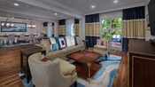Área de estar em uma suíte com acesso ao Captain’s Deck Club Level do Disney’s Yacht Club, mesa de jantar, oito cadeiras, três sofás, mesa baixa, aparador, TV e deck com três espreguiçadeiras