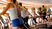 Men and women working out in blurred motion on exercise equipment