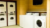 A laundry room with several washing machines and dryers
