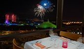 A restaurant table with a view of fireworks erupting over Magic Kingdom Park
