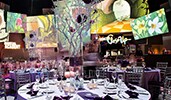 An event space with colorful monitors and colorful dining tables with whimsical woodsy table displays An event space with colorful monitors and colorful dining tables with whimsical woodsy table displays