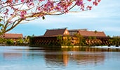 The exterior of Disney's Polynesian Village Resort, featuring a lake and Polynesian themed design