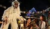 A stilt walker dressed in a yeti inspired costume greets Guests at a party by Expedition Everest
