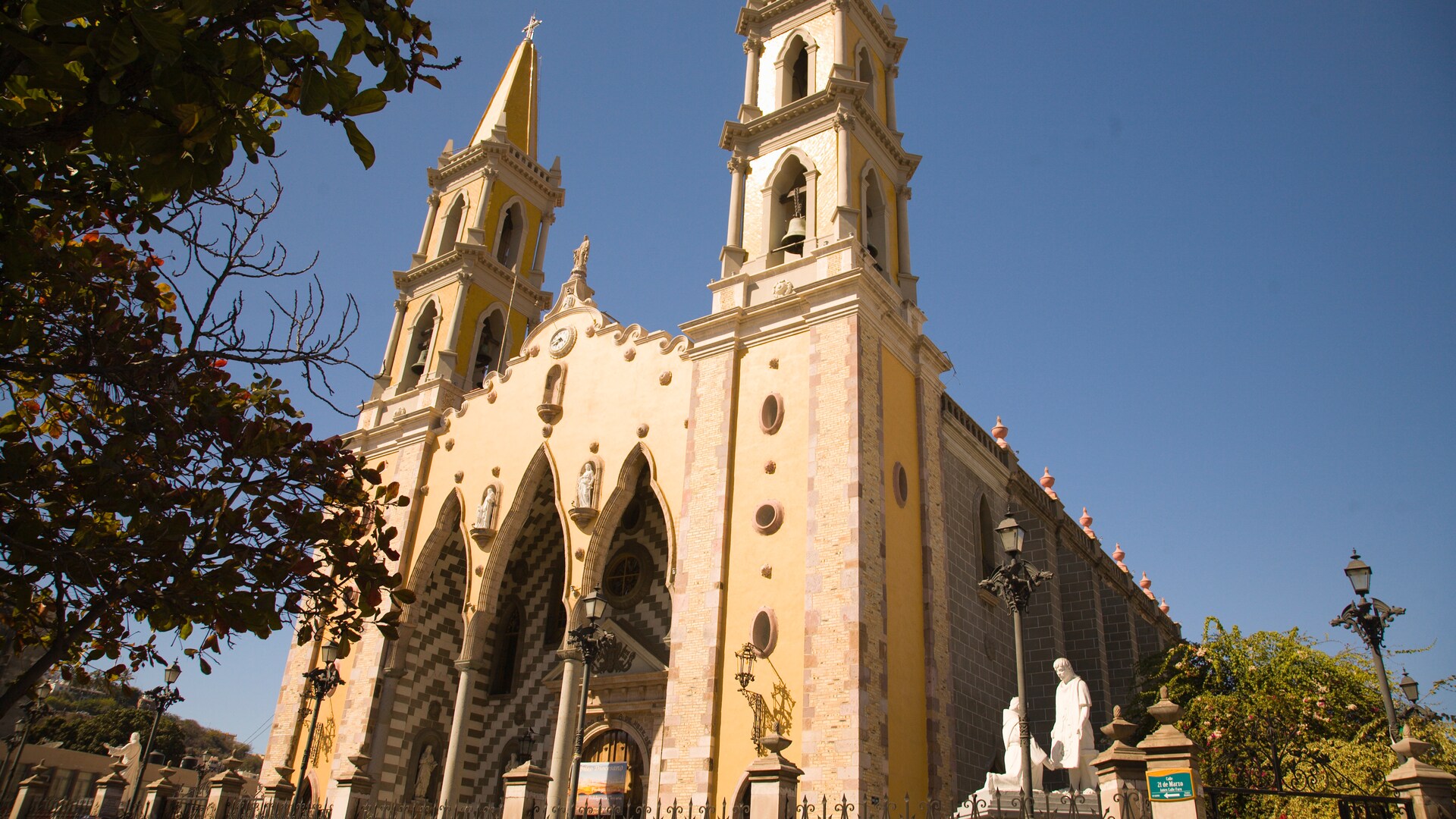 The Cathedral Basilica of the Immaculate Conception flanked by statues, trees and a fence