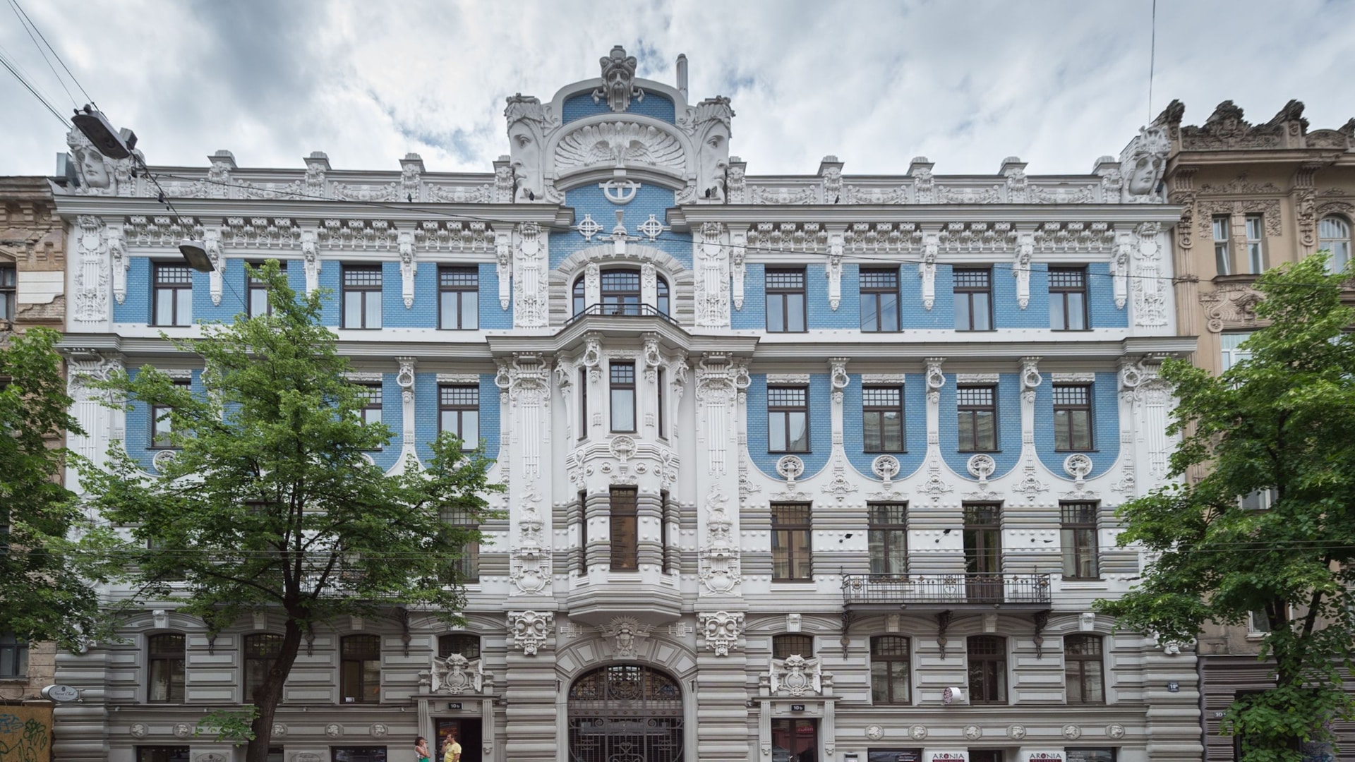 A large, ornate building with carvings of human faces among the details