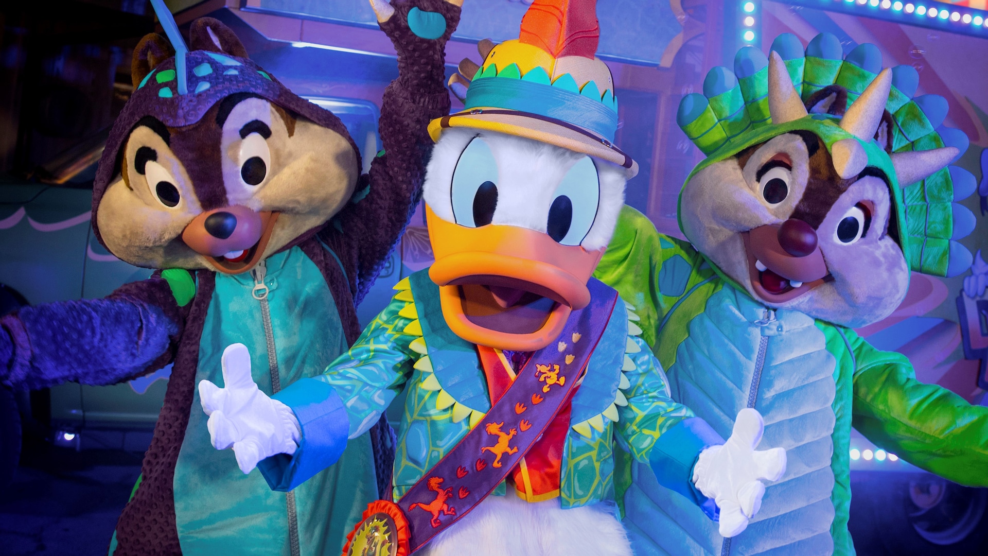 Chip and Dale dressed up as dinosaurs stand next to Donald Duck dressed in a safari outfit