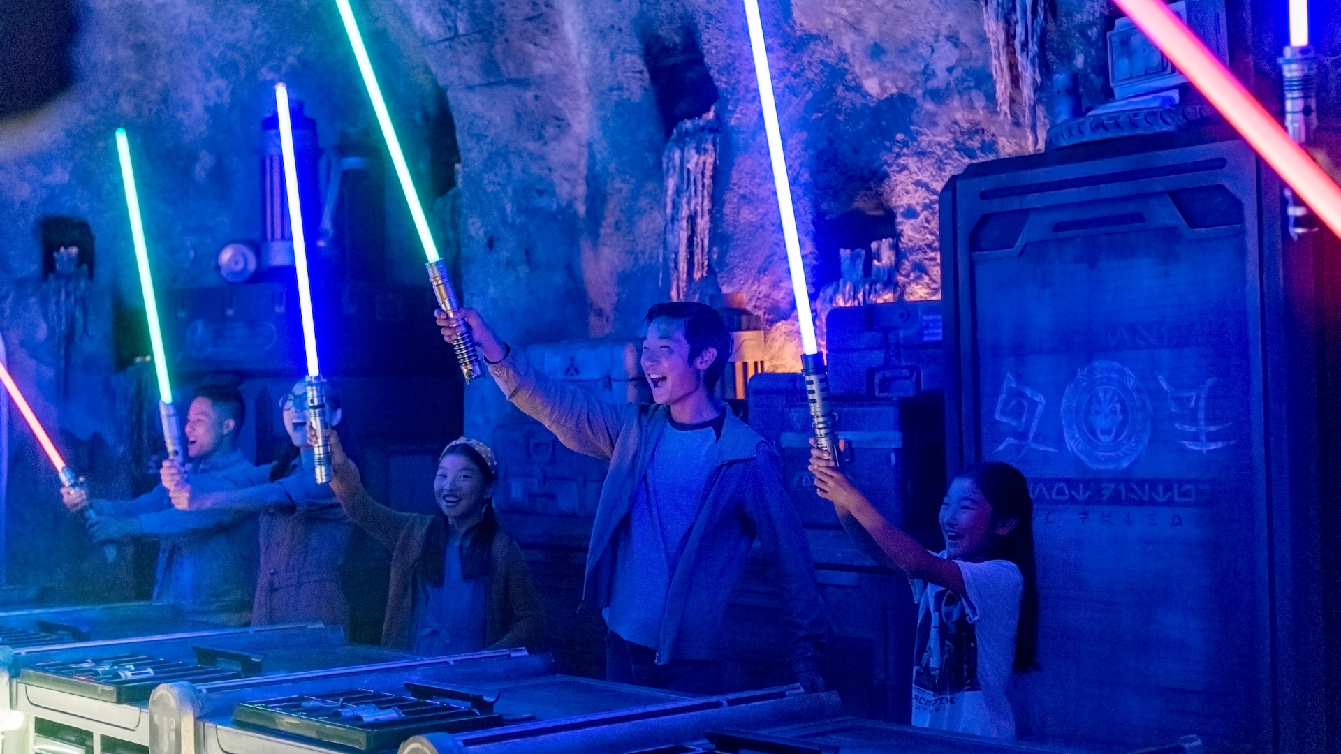 A family reacts with joy as their newly constructed lightsabers illuminate inside of metal cylinders for the first time