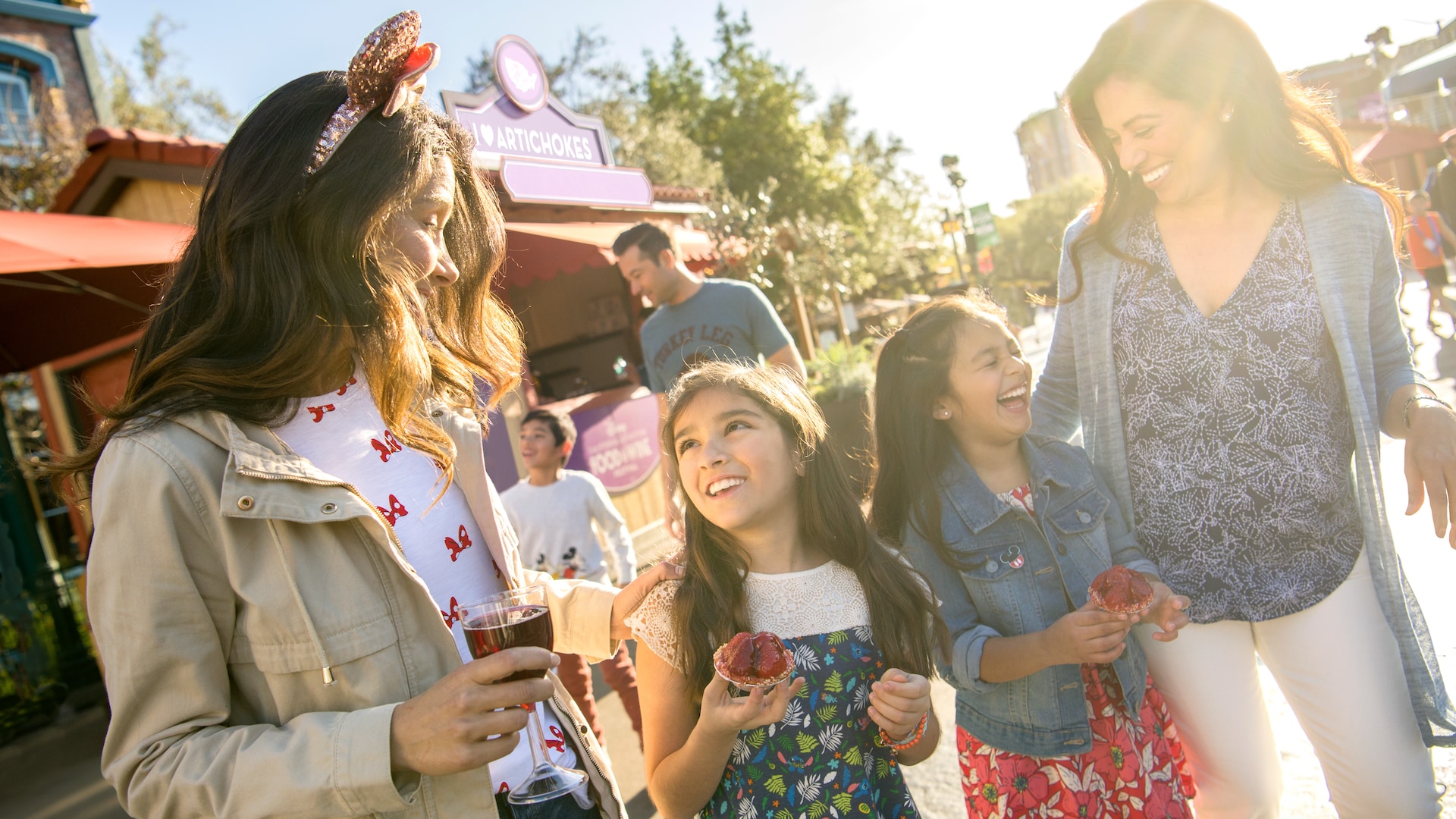 2 mothers and their daughters share a laugh over snacks at Disney California Adventure Park