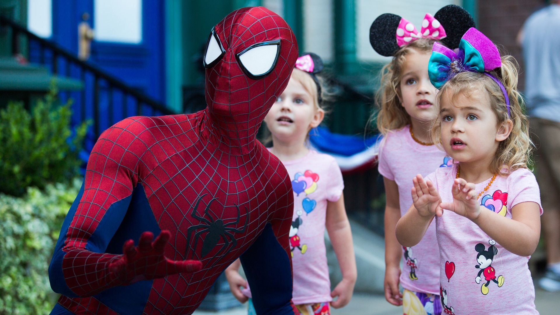 Spider Man strikes a kneeling action pose as 3 little girls look on