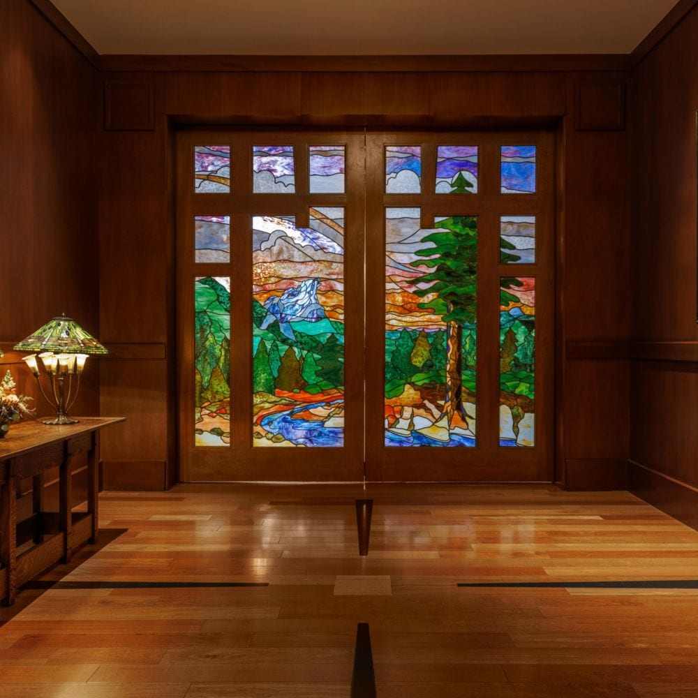 A wood paneled room at Disney's Grand Californian Hotel & Spa with stained glass doors depicting a mountain landscape