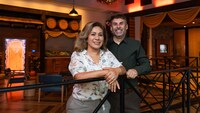 A smiling couple poses for a photo in Disney Vacation Club Golden Vine House, A Welcome Home Center, which is decorated for the holidays
