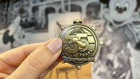A hand holds a pin that reads, Ears to 35 Years, Disney Vacation Club 
