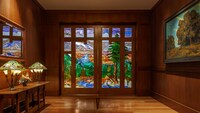 A hallway featuring a stained glass door depicting a river flowing through a mountain 