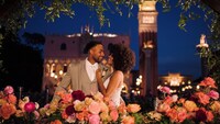 A bride and groom surrounded by flowers while standing amid the Italian style buildings of Italy Isola in Epcot