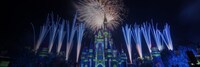 Aerial fireworks soaring above and flanking Cinderella Castle at night