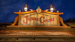 A wooden engraving that says "Jungle Cruise" on top of a building