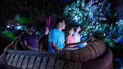 Guests enjoying the bioluminescence of Na’vi River Journey while they ride aboard a woven raft