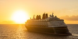 A Disney Cruise Line cruise ship sails on the sea towards the setting sun
