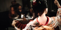 The back of a Japanese maiko in traditional dress, who is dancing with a fan in front of an audience The back of a Japanese maiko in traditional dress, who is dancing with a fan in front of an audience