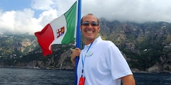 An Adventure Guide stands near water with a flag An Adventure Guide stands near water with a flag