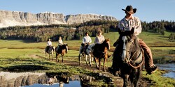 Cowboys ride horses along a trail
