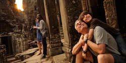 A dad and son view ancient ruins with other tourists nearby A dad and son view ancient ruins with other tourists nearby