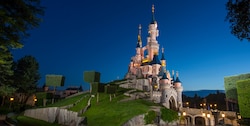 Sleeping Beauty Castle at Disneyland Paris is lit up against the nighttime sky