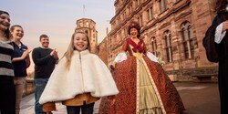 A girl wearing a fur jacket, her family and a woman dressed in a queen's costume outside a castle A girl wearing a fur jacket, her family and a woman dressed in a queen's costume outside a castle