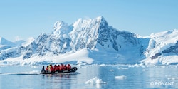 Group of parka clad Adventurers in a Zodiac boat navigating a strait to reach the snowy Antarctica shore Group of parka clad Adventurers in a Zodiac boat navigating a strait to reach the snowy Antarctica shore