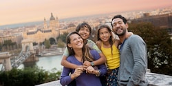 A family of Guests pose for a picture with a wide view of the city's historic buildings behind them A family of Guests pose for a picture with a wide view of the city's historic buildings behind them