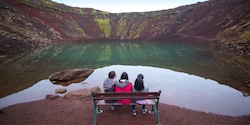 Three girls sitting on a bench overlooking a volcanic crater lake in Iceland Three girls sitting on a bench overlooking a volcanic crater lake in Iceland