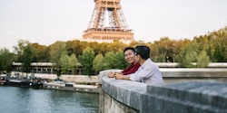 Two men with their arms resting on a wall near the Eiffel Tower Two men with their arms resting on a wall near the Eiffel Tower
