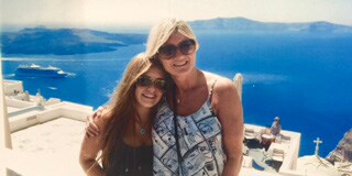 Marcy Ferruggia and her daughter pose for a picture with Santorini behind them.