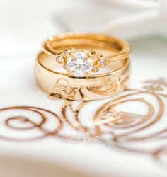 Gold wedding rings on top of a graphic of a Disney wedding carriage,