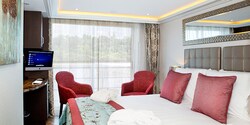 A Category C room, featuring a double bed, two club chairs and a sliding balcony door. A Category C room, featuring a double bed, two club chairs and a sliding balcony door.