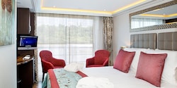 A Category C room, featuring a double bed, two club chairs and a sliding balcony door. A Category C room, featuring a double bed, two club chairs and a sliding balcony door.