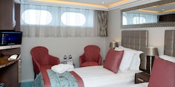 A Category E room, featuring two twin beds, two club chairs and a table. A Category E room, featuring two twin beds, two club chairs and a table.