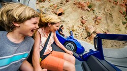 A mother and son take a tight turn on the Radiator Springs Racers track
