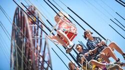 Smiling kids ride the Silly Symphony Swings at Disney California Adventure Park