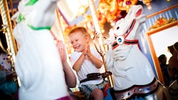 A happy boy rides a majestic horse on King Arthur Carrousel