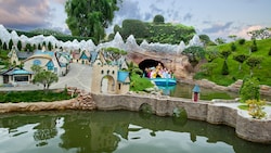 A Storybook Land Canal Boat full of Guests drifts gently past miniature villages