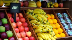 A fruit stand with apples, bananas and oranges