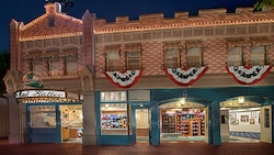 Patriotic flags cascading from the storefront as lights outside The Mad Hatter illuminate the night