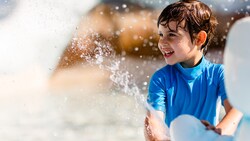 A boy squirts water from an ice sculpture at Tike's Peak, a polar-themed water play area