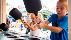 Um menino e uma menina com martelos em um jogo de acertar o dinossauro