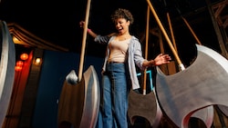 A young woman laughing while navigating between large swinging axe like pendulums in a darkened challenge room
