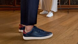 The feet of a man and a woman wearing Cole Haan sneakers