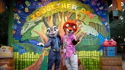 Judy Hopps and Nick Wilde posing together in front of a Zoogether Day sign