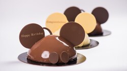 Three Mickey Celebration Cakes—milk chocolate, white chocolate and dark chocolate—in the shape of Mickey Mouse ear hats with ears, buttons and "Happy Birthday" on the ear of the front cake